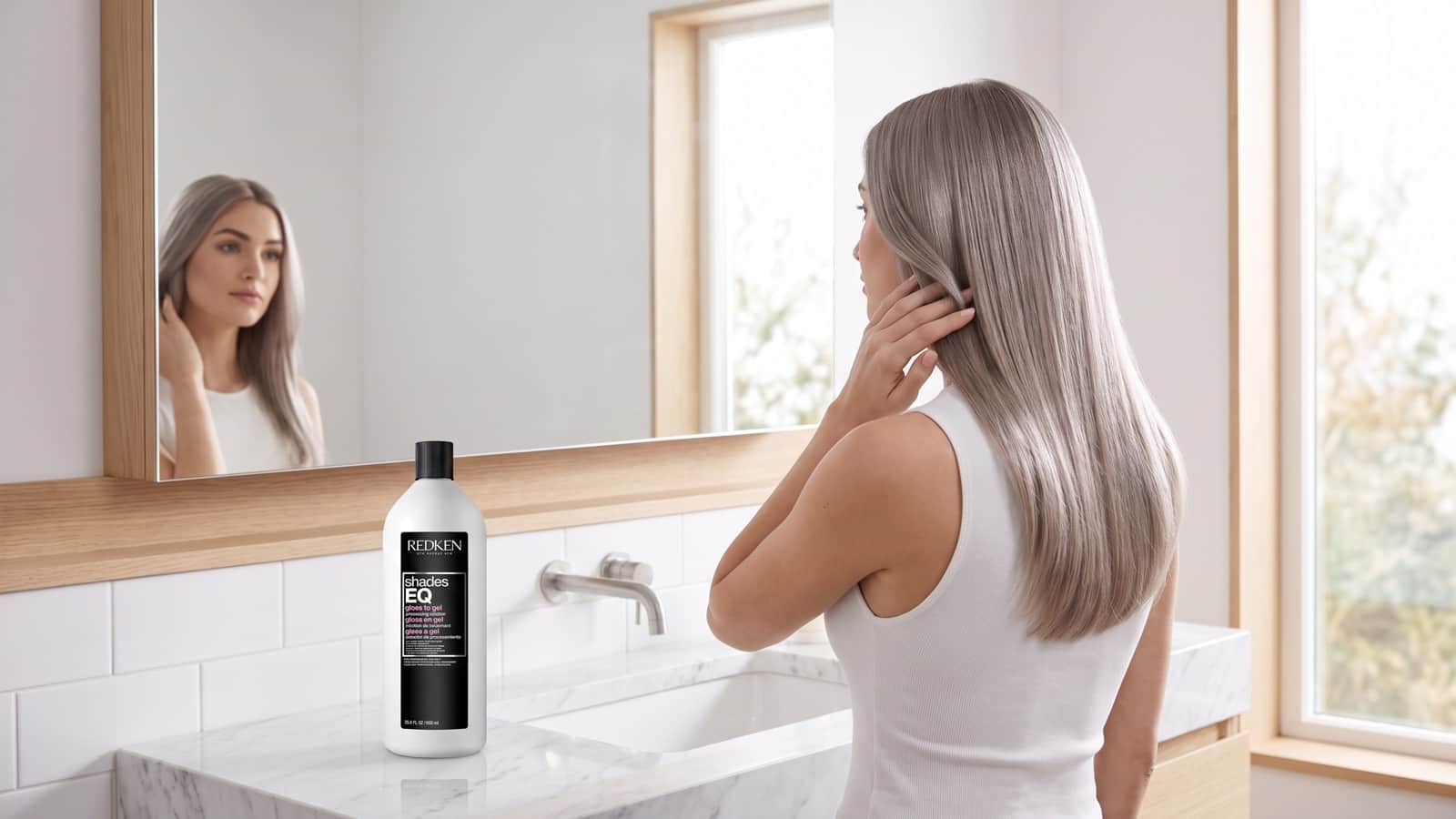 Femme aux cheveux blond cendré froid dans une salle de bains claire et minimaliste