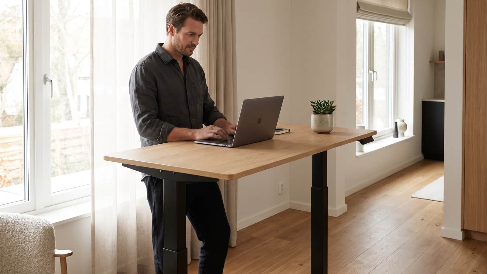 Personne travaillant debout à un bureau assis-debout réglable en hauteur dans un espace de télétravail lumineux