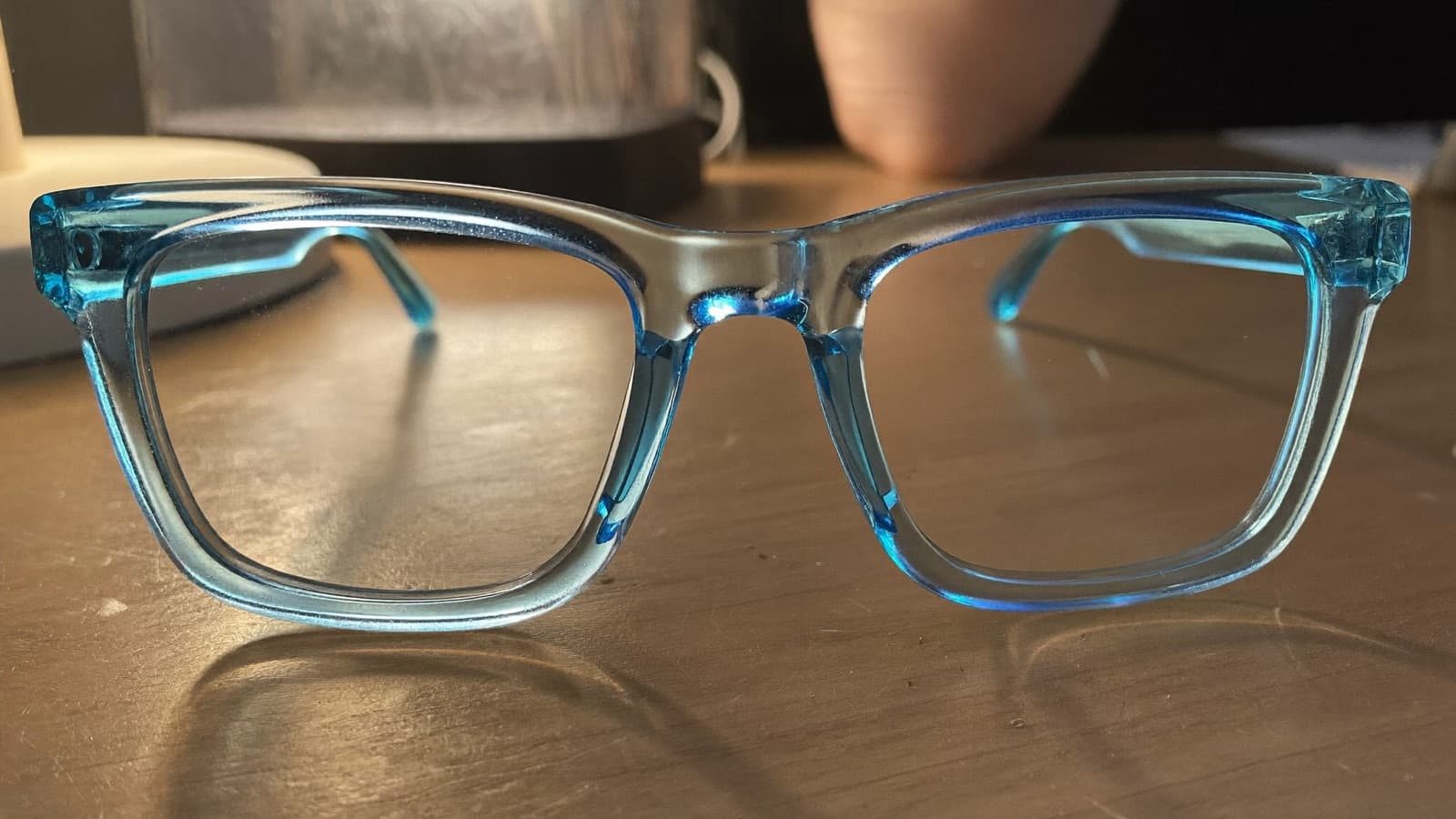 Blaulichtfilterbrille auf einem Holzschreibtisch neben einem Laptop am Abend